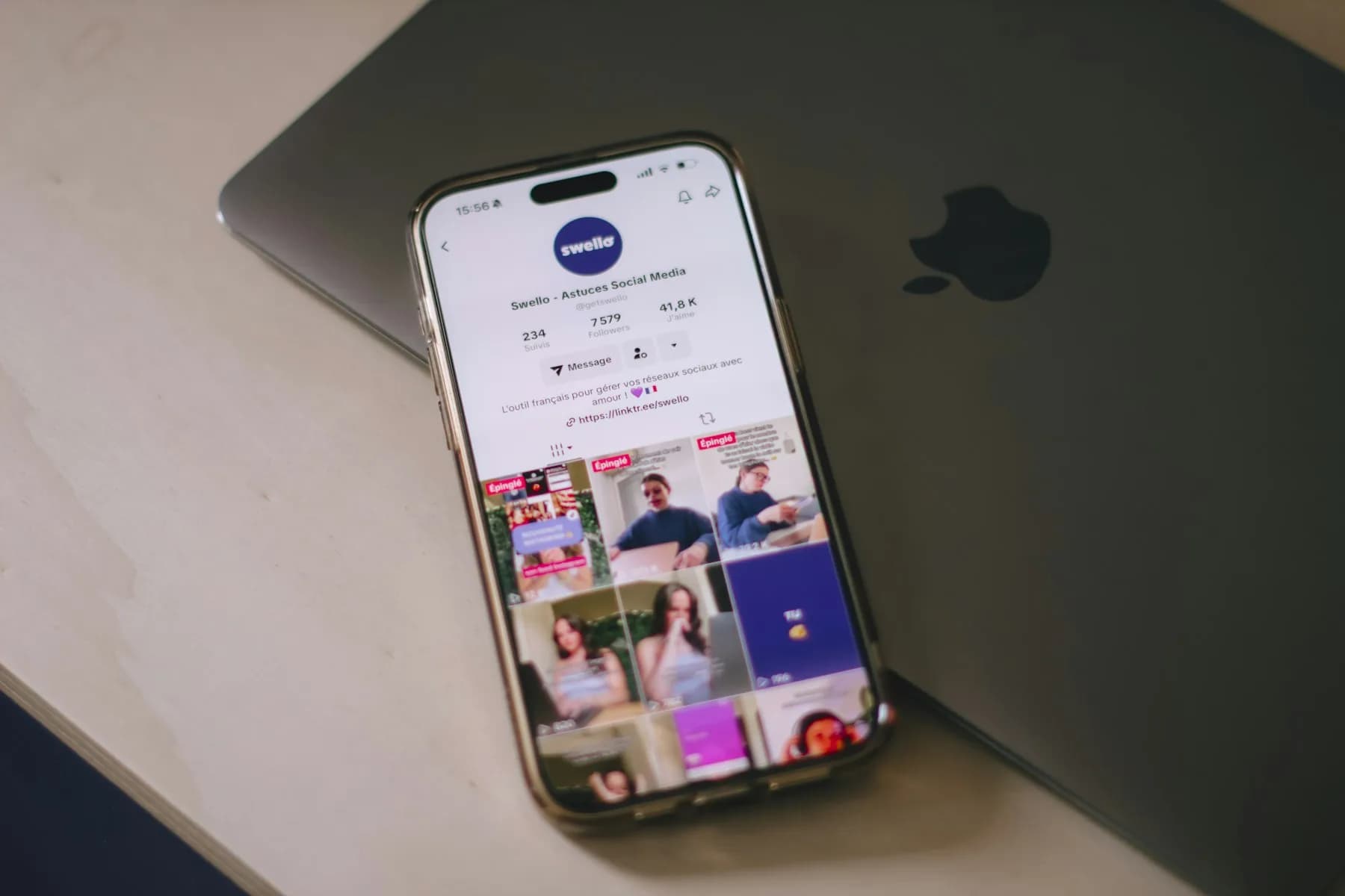 手机展示社媒账号主页，叠在 MacBook 上方——一次编辑、多平台分发的运营场景